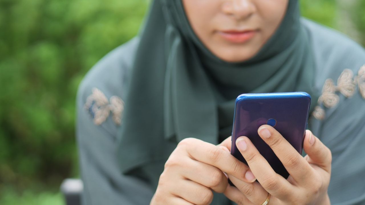 Close-up of a woman in hijab using a smartphone outdoors