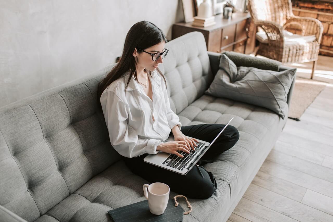 woman-sitting-on-modern-sofa-using-laptop