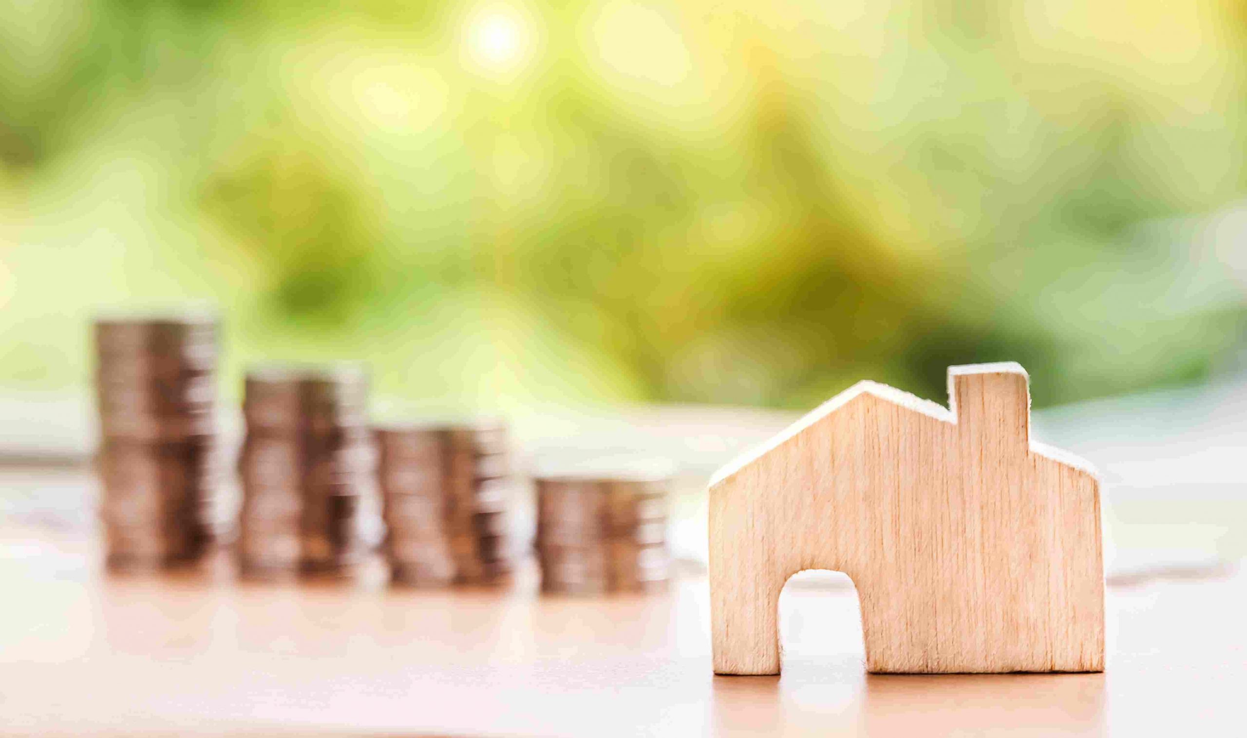 Stack of coins next to a wooden house