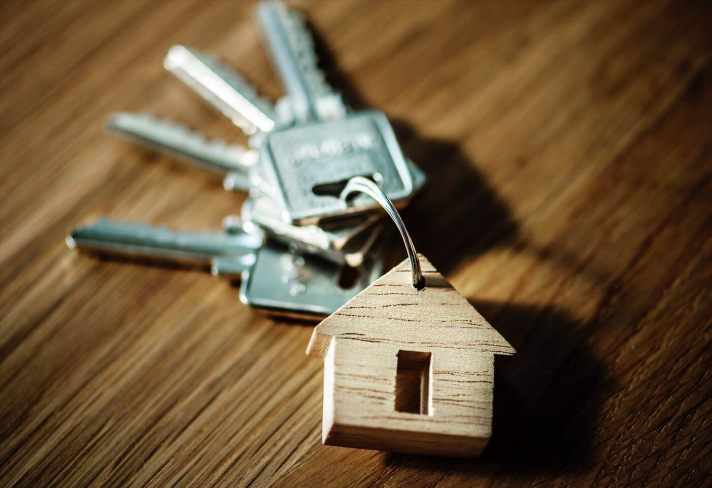 Silver keys on a house shaped keyring on a wooden surface