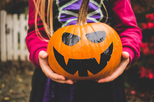 child-holding-pumpkin-in-halloween-costume