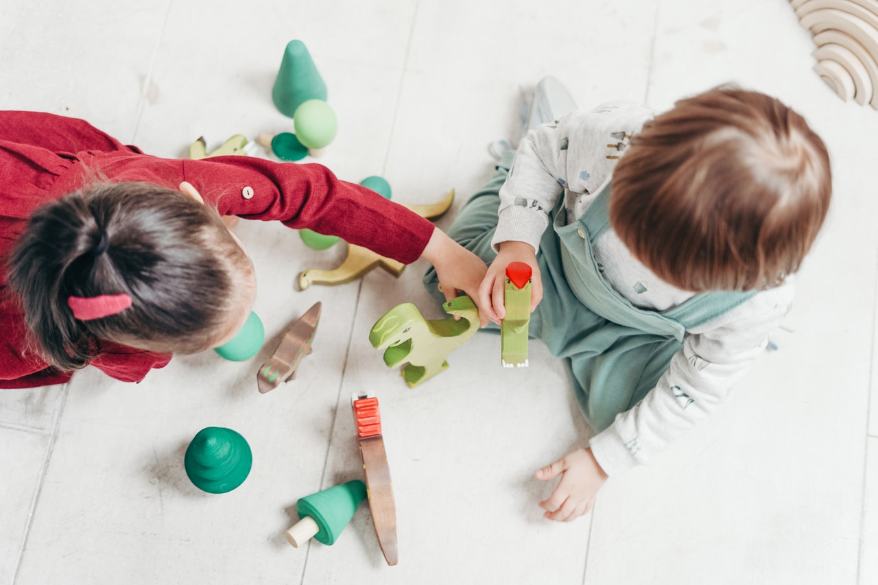 Overhead-view-of-two-children-playing-with-wooden-blocks