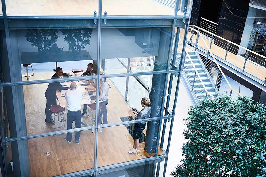 Smartly dressed people standing around a table inside glass office building