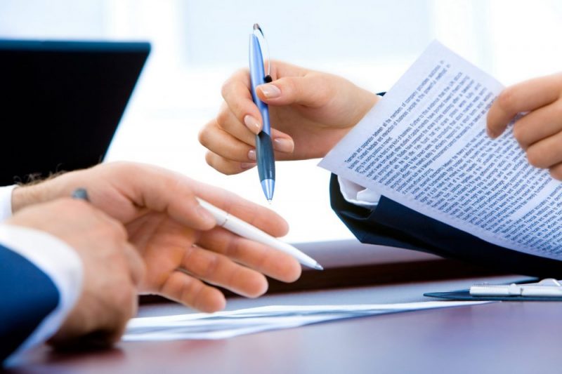 Two-people-signing-document-with-pen