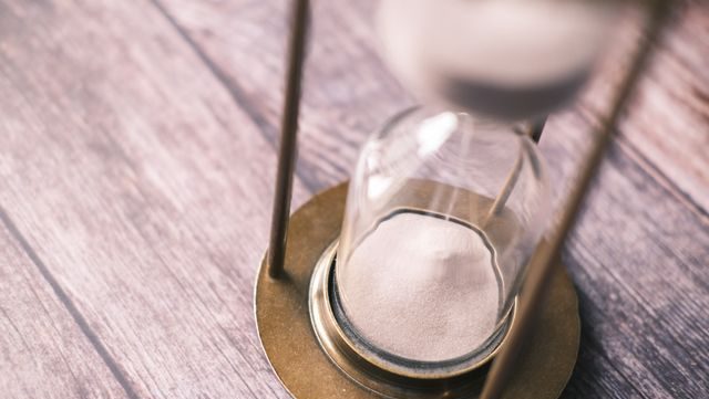 Close-up of a vintage hourglass with sand flowing on a wooden background