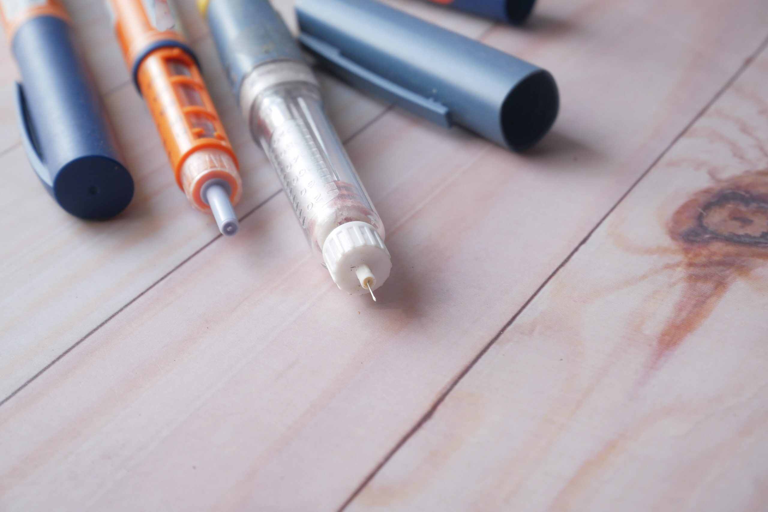 Four insulin pens sitting on top of a wooden table