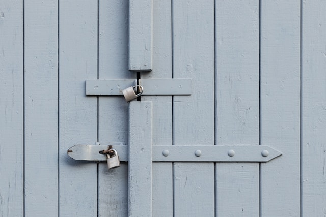 two-padlocks-on-grey-wooden-door