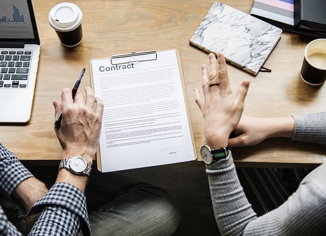 Two people looking at a contract on a light wooden table