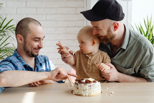 Male couple playing with baby at table