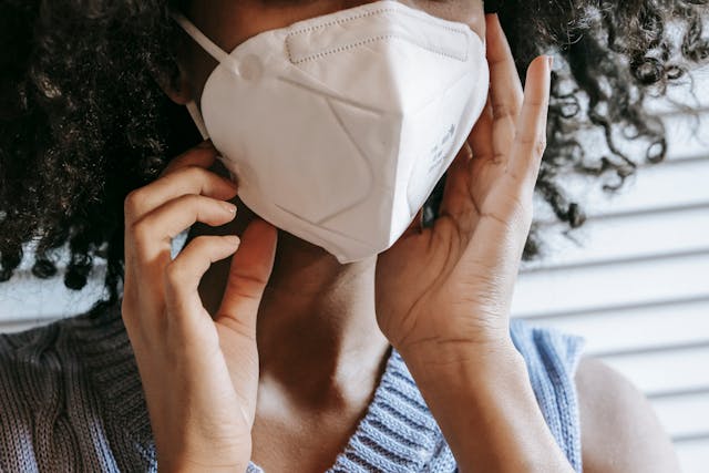 Close-up of a person wearing a white protective face mask which covers their nose and mouth