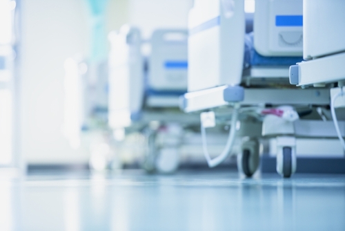 A row of empty hospital beds in a brightly lit room