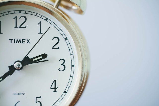 White and gold Timex analogue clock with black hands against white background