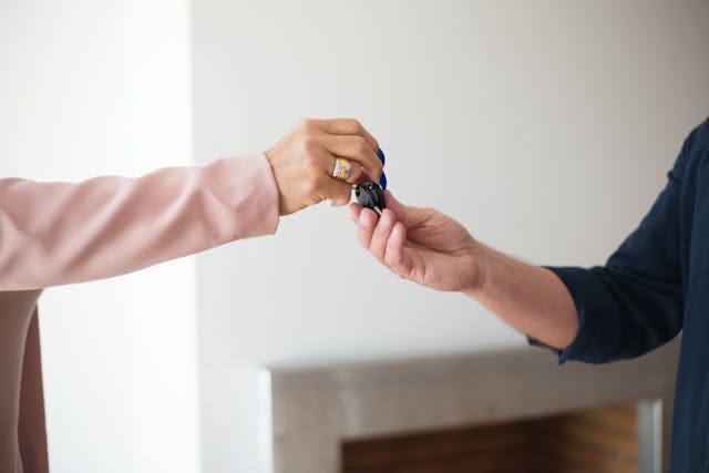 Close-up of person giving keys to another person