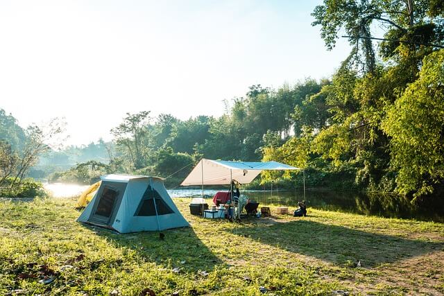 A tent on a camping site surrounded by trees and greenery.