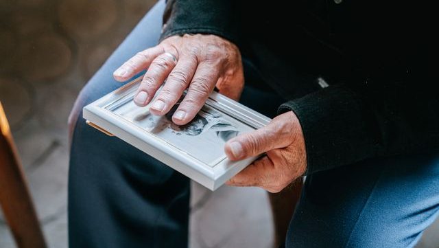 Elderly man holding a framed photo