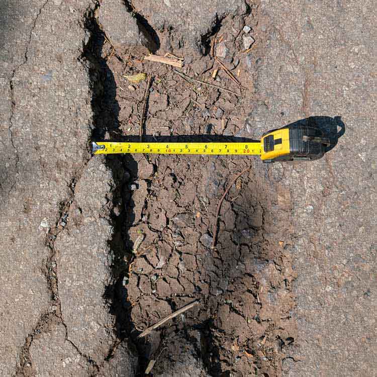 Tape measure measuring the width of a pothole