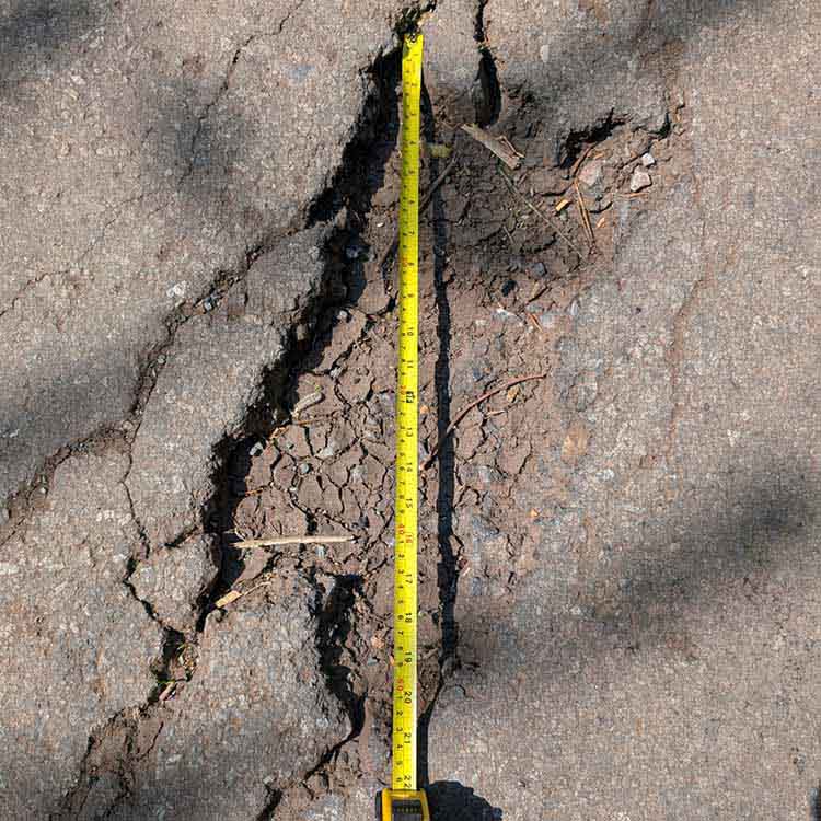 Tape measure measuring the height of a pothole