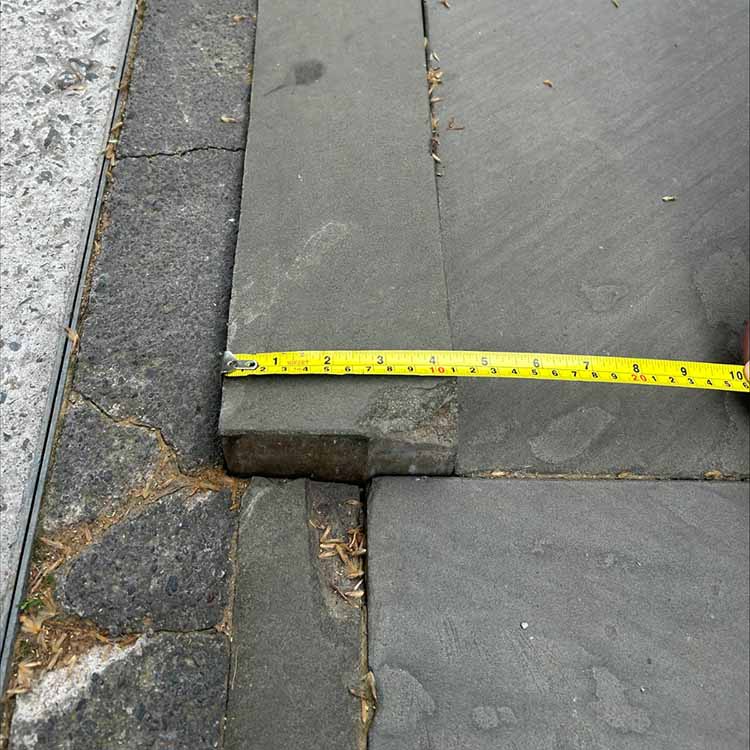 Yellow tape measure across a pavement slap