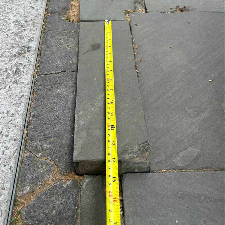 Yellow tape measure across a paving slab