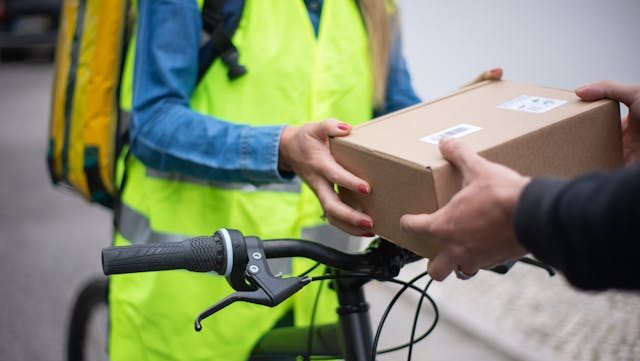 Bicycle courier handing over a package outdoors