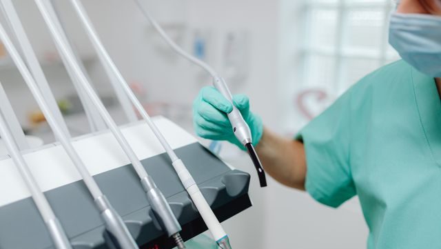Close-up of dental tools and equipment in a modern clinic with a dentist in scrubs