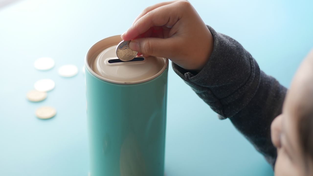 A child putting coins into a money tin