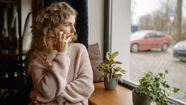 Woman in talking on a phone by the window