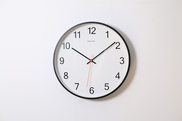 A round wall clock with black numbers and hands on a white face.