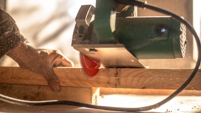 Circular saw cutting a wooden plank with visible dust particles