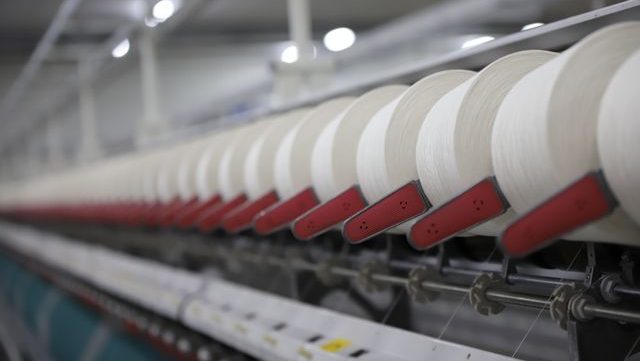 Close-up view of a textile production line showcasing white thread spools in a factory