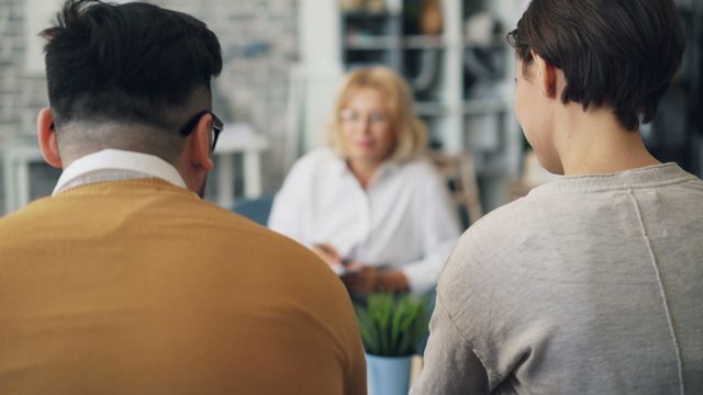 Two people engaged in a session with a professional on opposite sides of a table