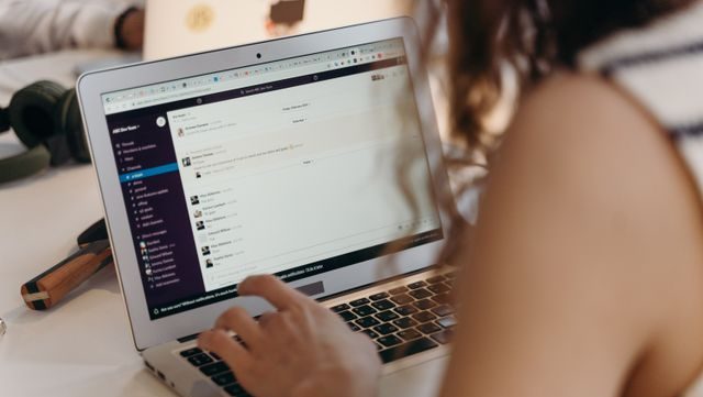 A businesswoman using Slack on a laptop in an office setting